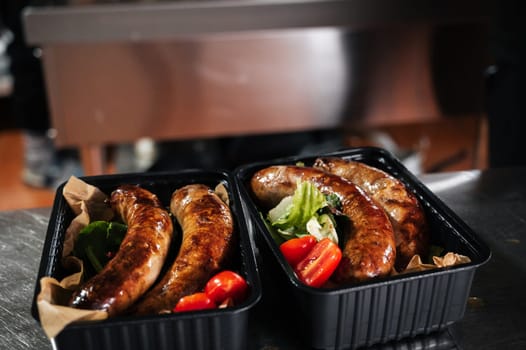 delicious fried cooked sausages in the kitchen in the restaurant in delivery containers
