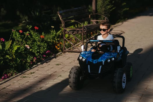 boy rides in a toy mini car in the park in summer