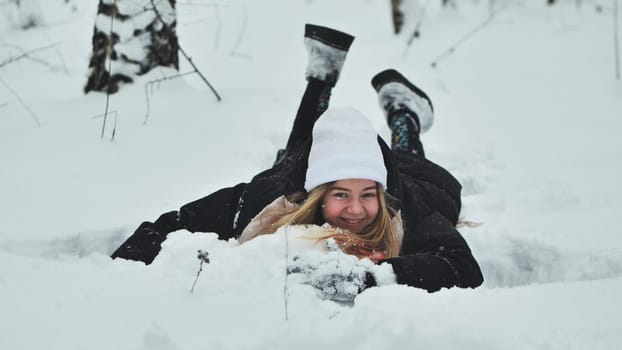 A girl falls on the snow in winter in the forest