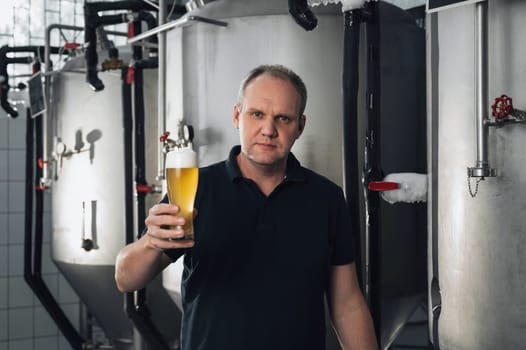brewer at a brewery with a glass of fresh beer