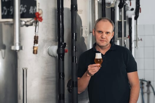 brewer at a brewery with a glass of fresh beer