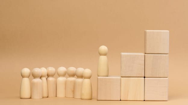 Wooden figures of men on a ladder made of blocks. The concept of career advancement, starting at work, achieving goals.