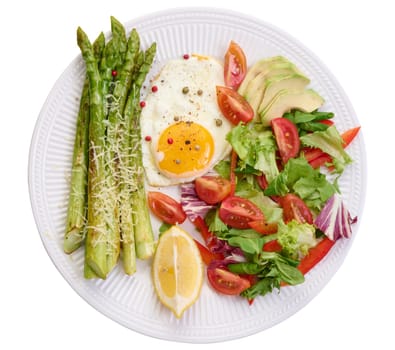 Round plate with cooked asparagus, fried egg, avocado and fresh vegetable salad, top view