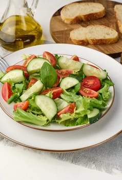 Salad with mozzarella, cherry tomatoes and green lettuce in a white round plate on the table
