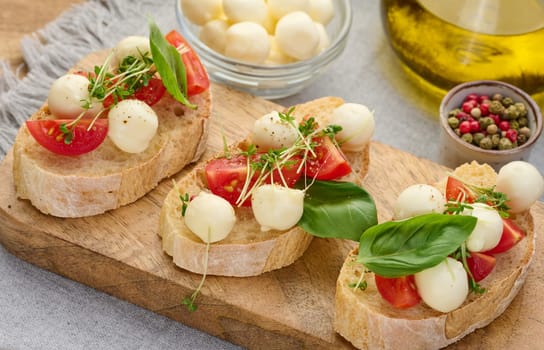 Round mozzarella, cherry tomatoes and microgreens on a piece of white bread, a healthy sandwich, close up