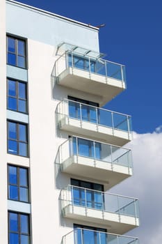 A modern urban design building with a striking facade featuring numerous windows and balconies, offering stunning views of the blue sky. It may be a condominium, commercial building, or tower block