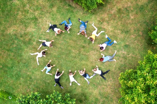 Top view of people standing in circle on green grass doing exercises