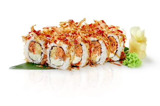 Sushi rolls with fried salmon, apple and cream cheese sprinkled with katsuobushi and unagi sauce presented on bamboo leaf with wasabi and pickled ginger on white background. Japanese authentic cuisine