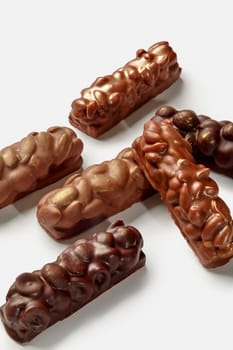 Variety of milk and dark chocolate bars with almonds, peanuts and hazelnuts, displayed against white background. Popular sweet snack concept