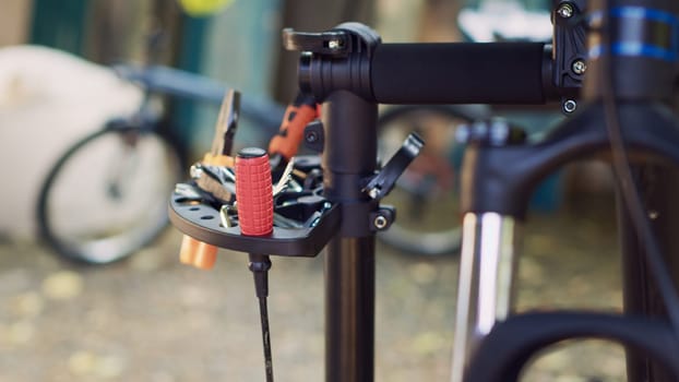 Zoom-in shot offering clear view of professional equipment displayed on repair-stand signifying readiness for bicycle maintenance outdoor. Various specialized work tools placed on bike workstand.