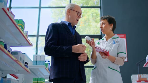 Aged man in chemist store asking pharmacist for medical opinion, needing treatment for irregular heartbeat. Druggist helping octogenarian client choose best pharmaceutical drug for heart problems