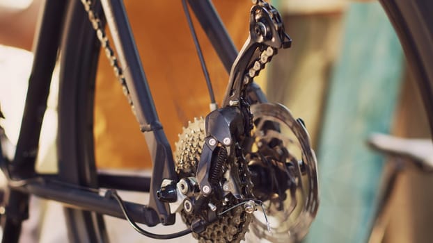 Close-up shot of man servicing and adjusting of bike rear derailleur and cogset outside for outdoor cycling. Detailed view of bicycle wheel revolving for close examination for damages.