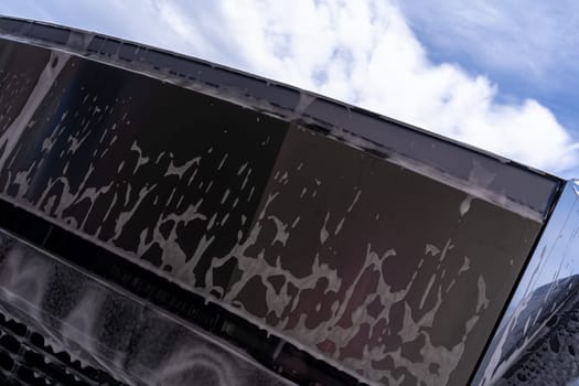 Denver, Colorado, USA-May 5, 2024-Close-up image of a Tesla Cybertruck being washed, showcasing the vehicle angular design and rugged tires. Water and soap suds cover the metallic surface, highlighting the unique texture and design elements of the electric truck.