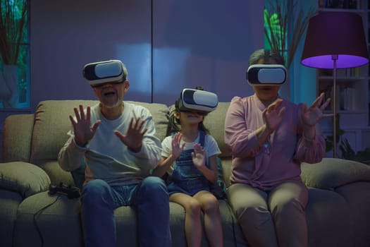 Asian elderly with child play VR video game, family entertainment, granddaughter and grandparents playing together exciting interesting video games using virtual reality headsets living room at home