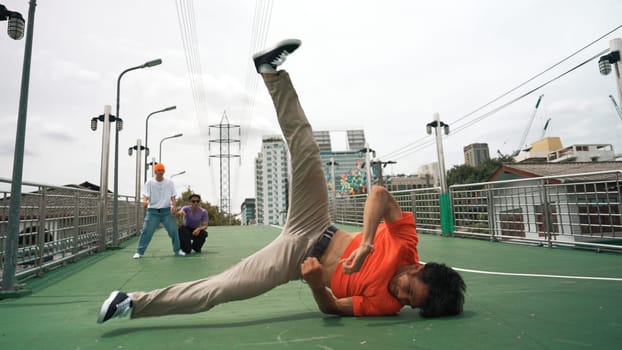 Young happy hipster perform break dancing or foot step with friend moving to hiphop music together. Skilled dancer doing freeze pose and waving hand. Modern lifestyle. Outdoor music 2024. Sprightly.