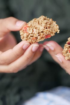 woman holding a Almond , Raisin and oat protein bar.