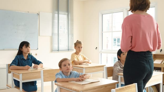 Back view of caucasian teacher teach diverse student while standing at blackboard. Professional instructor explain classwork while student looking and listen carefully. Education concept. Pedagogy.