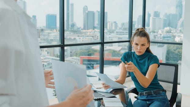 Professional female investor listening businessman present start up project statistic. Back view of businessman shows graph while manager using laptop analysis data at cityscape view. Tracery