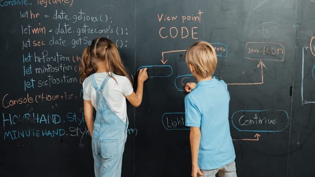 Caucasian girl and smart boy writing blackboard with engineering prompt or coding, programing system written in STEM technology classroom. Young cute student working together at blackboard. Erudition.