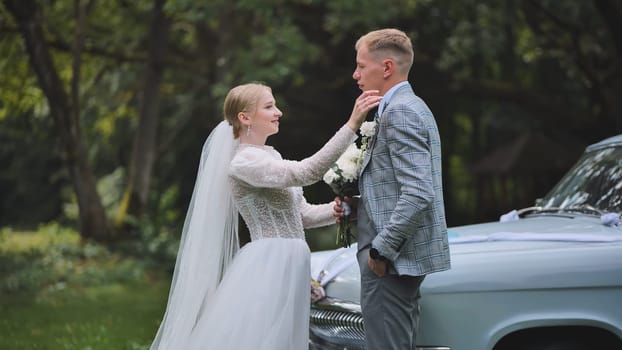 The bride and groom linger by the retro car on their wedding day