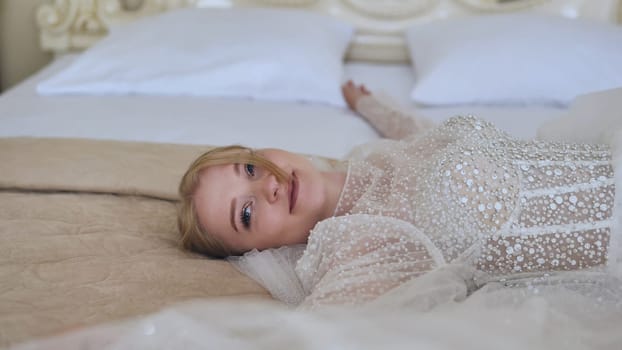 The delicate bride lies and poses on the bed