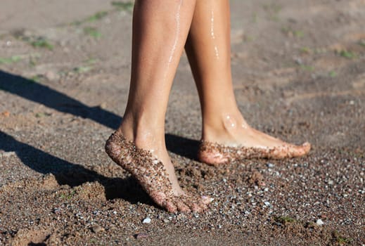 Nude female legs close up stepping on the sea sand on the coast.  Nudity and healthy lifestyle concept