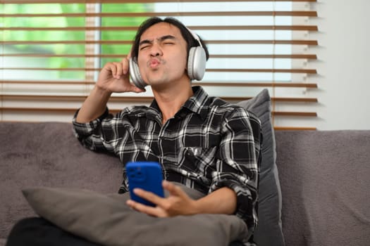Happy young man with wireless headphones enjoying his favorite music playlist on mobile phone.