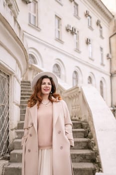 woman in elegant coat and hat against an intricate architectural backdrop, harmoniously blending modern fashion with historical allure. The soft daylight adds to its timeless appeal