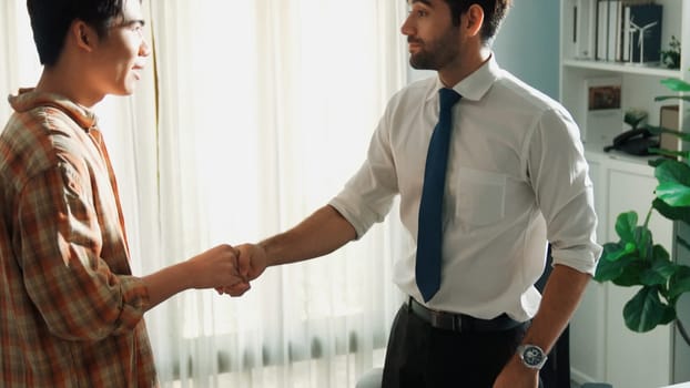 Professional architect engineer sitting while explain house plan to manager. Aerial view of diverse designer shaking hands while talking about building construction at meeting room. Alimentation.