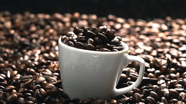 Close up of coffee bean falling in to coffee cup surrounded by pile of beans. Dropping aromatic blending bean in to white cup. Top view of coffee drop in to glass with black background. Comestible.