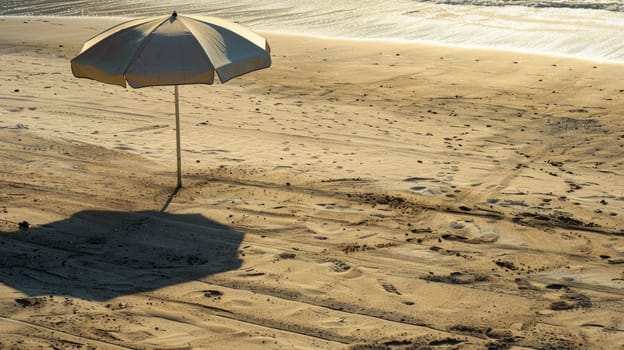 An umbrella rests on the sandy shore of the beach, overlooking the vast expanse of water. Travelers enjoy the scenic landscape as they relax on the shore AIG50
