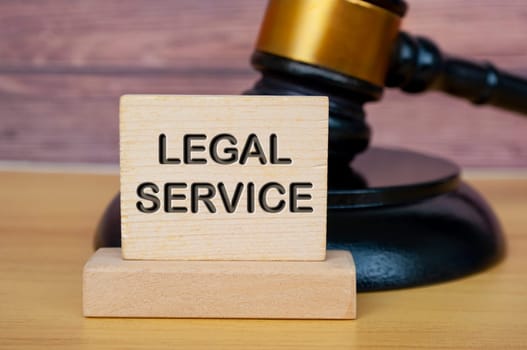 Legal service text engraved on wooden block with gavel background. Legal and law concept