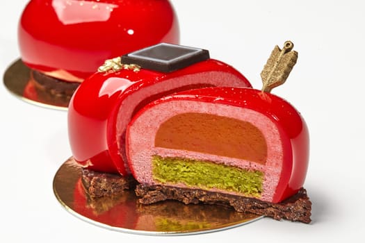 Delicious red glazed heart-shaped pastry with layers of strawberry mousse, sea buckthorn confit and pistachio sponge cake on chocolate streusel, decorated with golden arrow. Romantic dessert