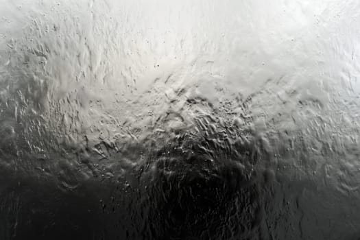 Black and white photo of water flowing down a glass window. AIG51A.