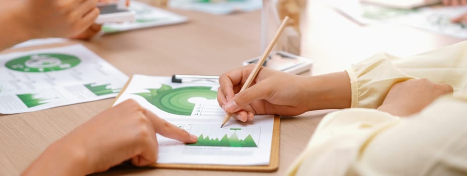 Professional businesswoman interested in invested in green businesses when he see rising graph on table with environmental document scatter around. Closeup. Focus on hand. Delineation.