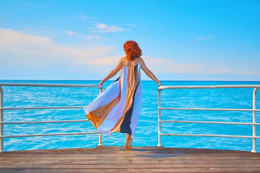 Behind girl on pier. Back view of red head girl on pier.