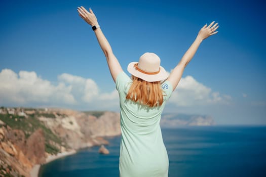 Woman tourist sky sea. Happy traveler woman in hat enjoys vacation raised her hands up.