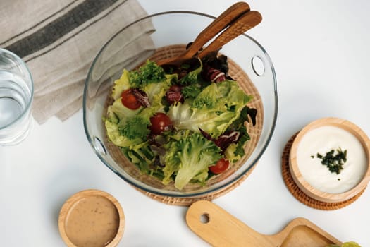 Fresh mix vegetable salad in glass blow beside dish of double meat hamburger and wholegrain bun on meal cooked by homemade serving white table. Preparing special dish menu list's restaurant. Infobahn.