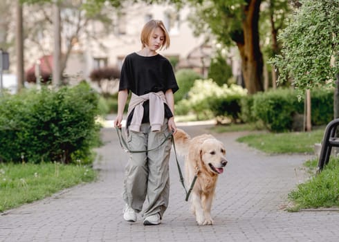 Girl With Golden Retriever Strolls On Street With Dog