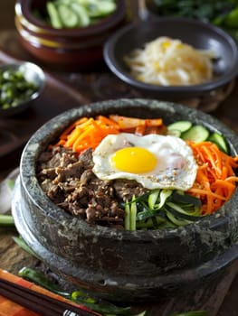 Elaborate Korean bibimbap served in a stone bowl, featuring assorted vegetables, beef, and a sunny-side-up egg. A traditional Korean dish known for its vibrant colors and flavors