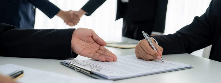 Two business executive shake hand in boardroom, sealing agreement merging two company. Handshake symbolize business partnership and cooperation. Corporate acquisition and merger concept. Shrewd