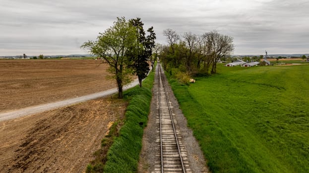 A train is traveling down a track next to a field. The train is black and steam is coming out of the front