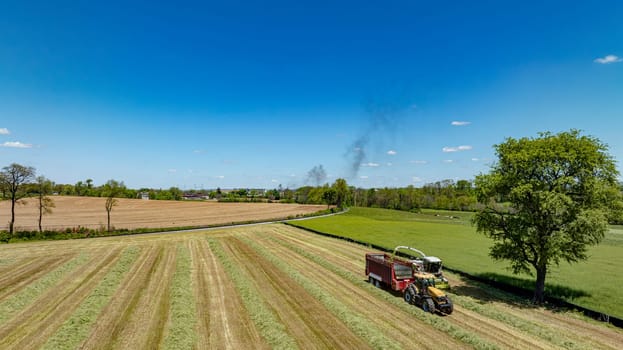 An expansive aerial photograph highlights the dynamic nature of farming with active harvesting machinery in the foreground, set against a backdrop of mixed greenery and brown fields.