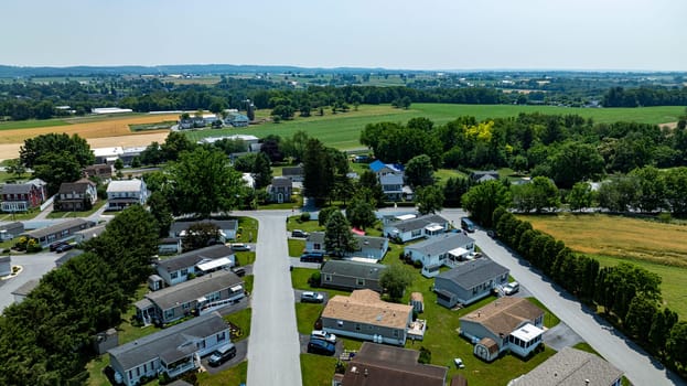 Overhead aerial view of a suburban Mobile, Prefab, Manufactured, neighborhood park, featuring rows of homes, neatly trimmed lawns, and parked cars