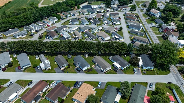 Overhead aerial view of a suburban Mobile, Prefab, Manufactured, neighborhood park, featuring rows of homes, neatly trimmed lawns, and parked cars