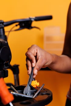 Black woman hand seen in close-up selecting and analyzing equipment from bike repair-stand. Photo focus on specialized bicycle maintenance tools being held and arranged by african american woman.