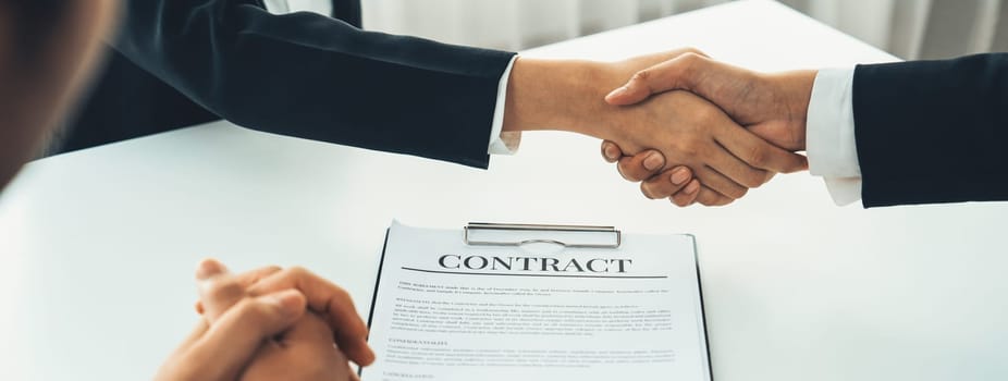 Two business executive shake hand in boardroom, sealing agreement merging two company. Handshake symbolize business partnership and cooperation. Corporate acquisition and merger concept. Shrewd