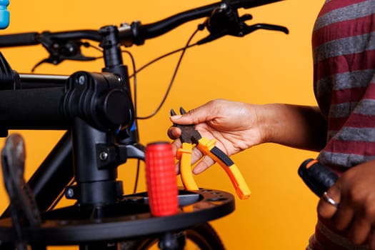 Detailed shot of a black woman hand holding and arranging bicycle servicing equipment. Close-up of a plier and other specialized tools being organized on bike repair stand by african american person.