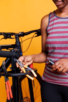 Detailed shot of female african american pair of hands holding plier and screwdriver from toolkit for bicycle maintenance. Skilled black individual examining and arranging professional tools.