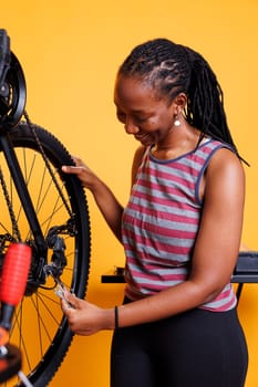 Sports-loving african american lady securing and tightening bicycle hub and axle. Image showing active youthful black woman holding professional equipment for bike maintenance.